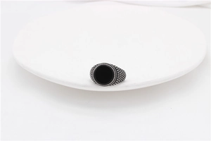 Macro detail of retro stainless steel ring featuring a black oval gemstone and textured band