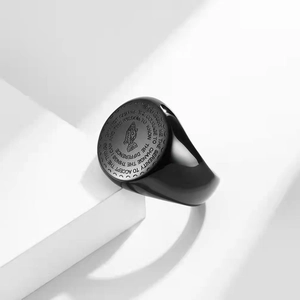 Close-up of black steel signet ring with praying hands and engraved serenity prayer