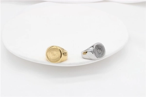 Macro view of gold and silver steel signet rings with prayer hands and engraving