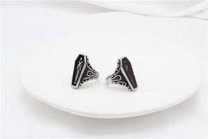 Macro shot of gothic coffin rings with skeleton engraving and vintage patterns on white plate