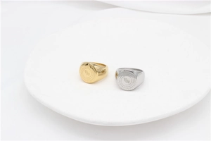 Detailed view of gold and silver signet rings featuring engraved praying hands design
