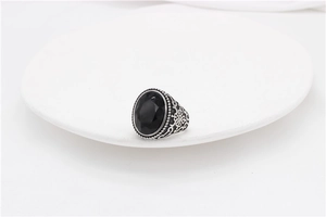 Macro view of vintage silver steel ring with oval black stone and ornate carvings