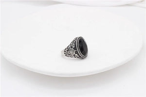 Close-up of vintage steel ring with black oval gemstone and floral relief details