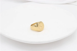 Macro detail of gold signet ring featuring praying hands and serenity prayer engraving