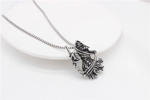 Detail of vintage silver Grim Reaper pendant featuring skeletal figure with a long scythe
