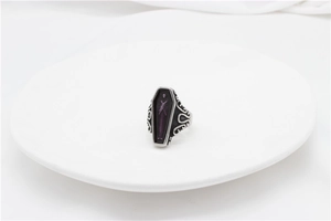 Macro detail of gothic coffin ring with purple interior skull and scrollwork on the band