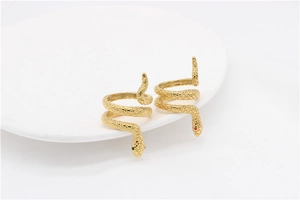 Detail of two golden snake rings with scaled texture and red or green gemstone eyes