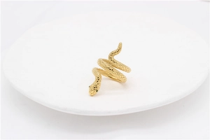 Detail of gold snake ring featuring green gemstone eyes and textured scales finish