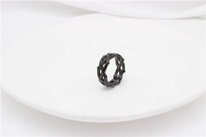 Detailed view of black thorn crown ring with hollow woven pattern on white plate