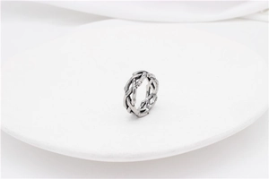 Macro shot of silver thorn-textured steel ring displayed on a white round pedestal