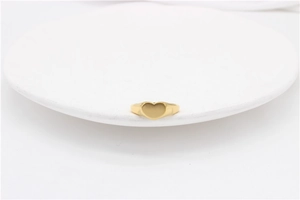 Flat minimalist heart-shaped gold ring with a matte finish on a white ceramic plate