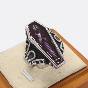 Gothic mummy coffin ring with purple enamel inlay and skeleton bird on a wood stand
