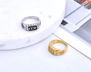 Detail of gold and silver FTW signet rings with wing relief on white marble