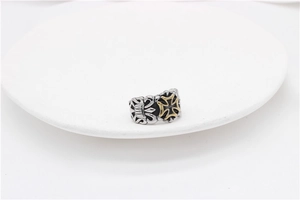 Macro detail of gothic punk cross ring featuring embossed texture and two-tone finish