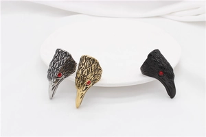 Detailed view of three eagle head rings in silver, gold and matte black with red stone eyes