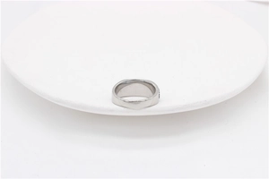 Detailed side view of a wide polished stainless steel ring on a minimalist white stand