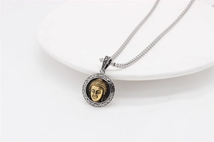 Detailed view of the gold Buddha head relief on a textured silver stainless steel pendant