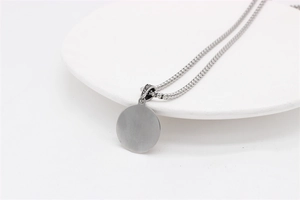 Close-up of minimalist silver stainless steel round pendant with beaded chain necklace