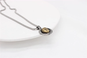 Detailed close-up of a vintage two-tone Buddha pendant with a silver square link chain