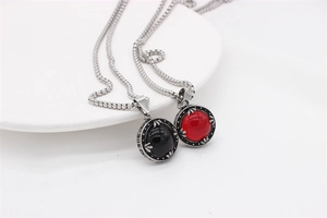 Close-up of vintage stainless steel necklaces with red and black round gemstones in white dish
