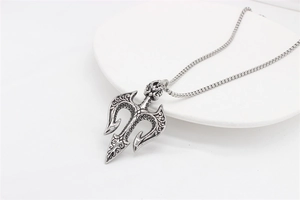 Macro detail of retro trident shield pendant with intricate floral engravings and box chain