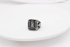 Detailed close-up of retro Masonic signet ring featuring compass and square on white tray