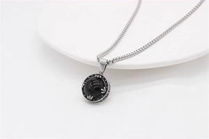 Macro detail of round black stone pendant with vintage floral metal carving and box chain