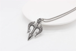 Detail of vintage trident pendant featuring intricate floral engravings and distressed steel finish