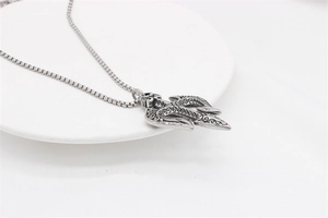 Macro detail of silver trident pendant with vintage scrolls and square box chain