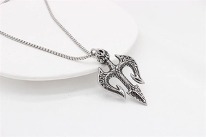 Close-up of vintage silver trident pendant with intricate floral engraving on a box chain