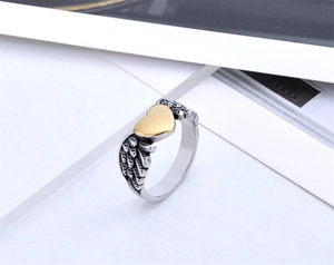 Detailed close-up of retro titanium steel ring with gold heart and silver wings