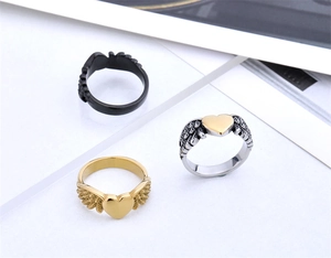 Detailed view of angel wing heart rings in black, gold, and two-tone polished steel