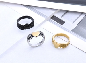 Detailed view of angel wing heart rings in black, gold, and silver stainless steel finishes