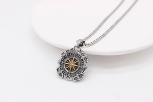 Detailed close-up of retro compass star pendant with gold star accent and silver box chain
