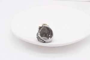 Makro-Detail des Vintage-Totenkopf-Blitzrings aus Stahl mit Goldakzenten auf Tablett
