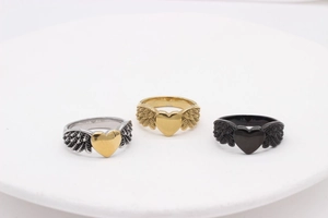Detail of angel wing heart rings in silver, gold and black finishes on white tray