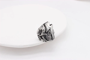 Makroaufnahme des Retro-Silber-Totenkopfrings mit Blitzdetails auf einem weißen Teller