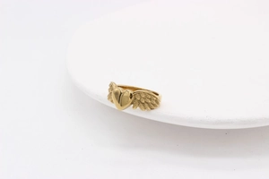 Macro view showing the polished golden heart and feather wings detail on the steel ring