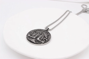 Close-up of vintage Egyptian Anubis coin pendant with silver box chain on a white tray