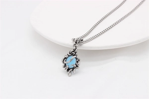 Close-up of vintage steel pendant featuring blue gemstone and intricate hollow pattern