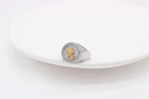 Gros plan détaillé d'une bague chevalière argentée avec des mains en prière dorées