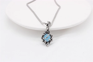 Detailed close-up of blue sapphire pendant with vintage silver flame pattern on white tray
