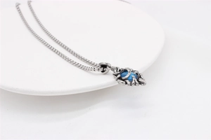 Macro detail of gothic silver pendant featuring a blue gemstone with vine pattern
