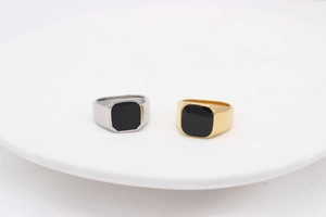 Détail macro de chevalières carrées or et argent avec incrustation noire sur céramique