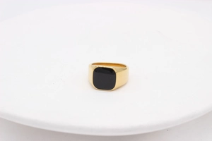 Détail macro d'une bague chevalière dorée avec un insert carré en onyx noir poli