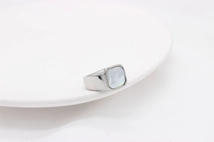 Macro d'une bague minimaliste en acier titane argenté avec nacre carrée incrustée
