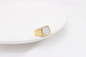Vue détaillée d'une bague chevalière dorée avec incrustation carrée de nacre blanche