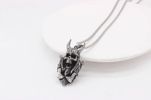 Close-up of vintage viking skull pendant necklace in silver finish on a white plate