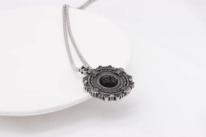 Macro view of gothic silver necklace with relief engraving and central black gemstone
