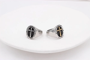 Macro detail of retro cross signet rings in silver and gold-tone steel finish